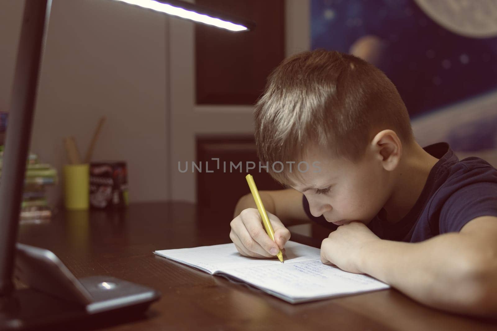 boy doing homework in children room in a notebook with a pen by PopOff