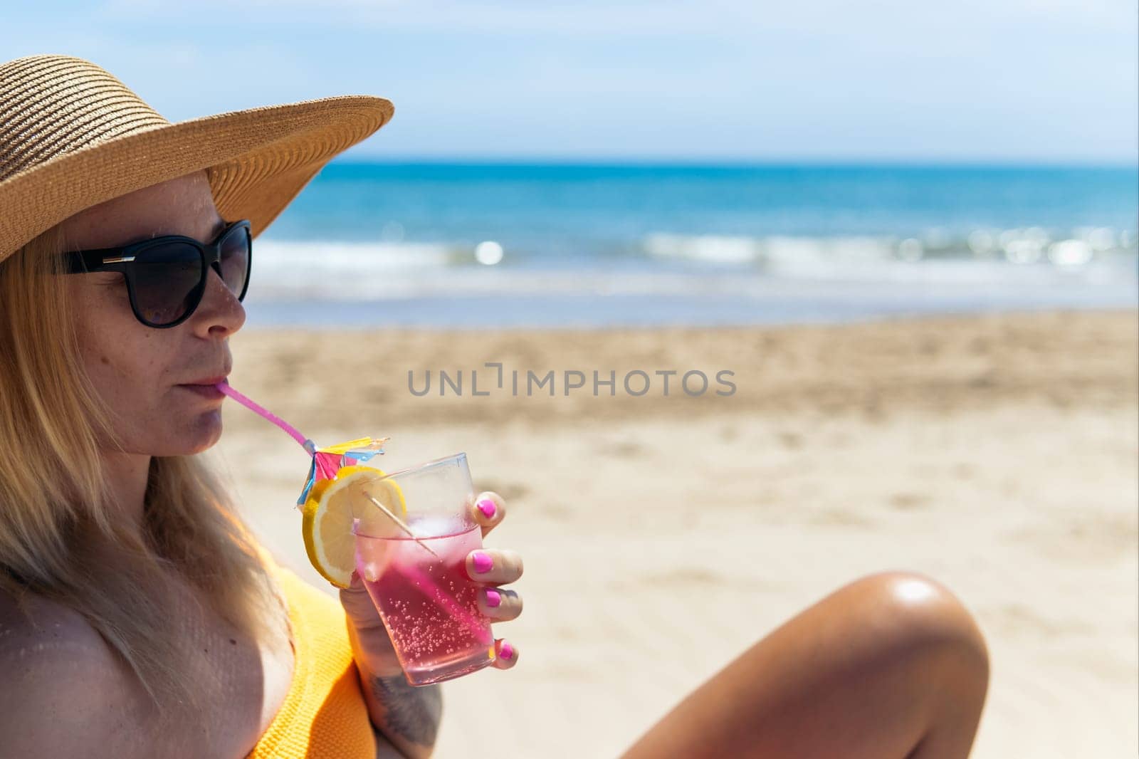 Happy young girl drinks a cocktail and rests in a sun lounger on the beach, space for inscription by PopOff