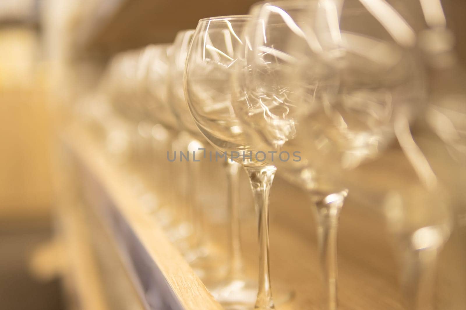 empty glass goblets for wine and other drinks on a wooden shelf on a blurred background. High quality photo