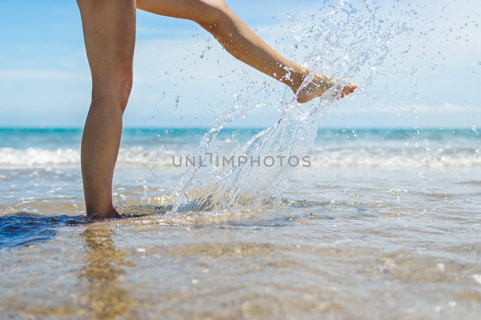 Vacation concept. Close up of female legs walking by the beach. by PopOff