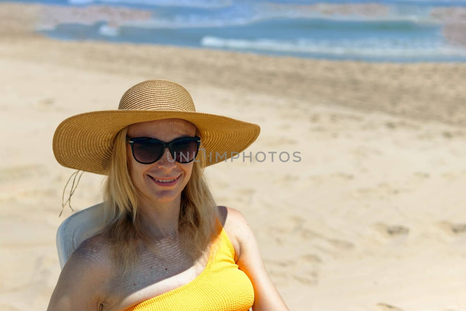 Beautiful seascape with a girl, a slender girl in a hat and swimsuit relaxes and lies on a sun lounger on the beach alone happy, there is a place for an inscription. High quality photo