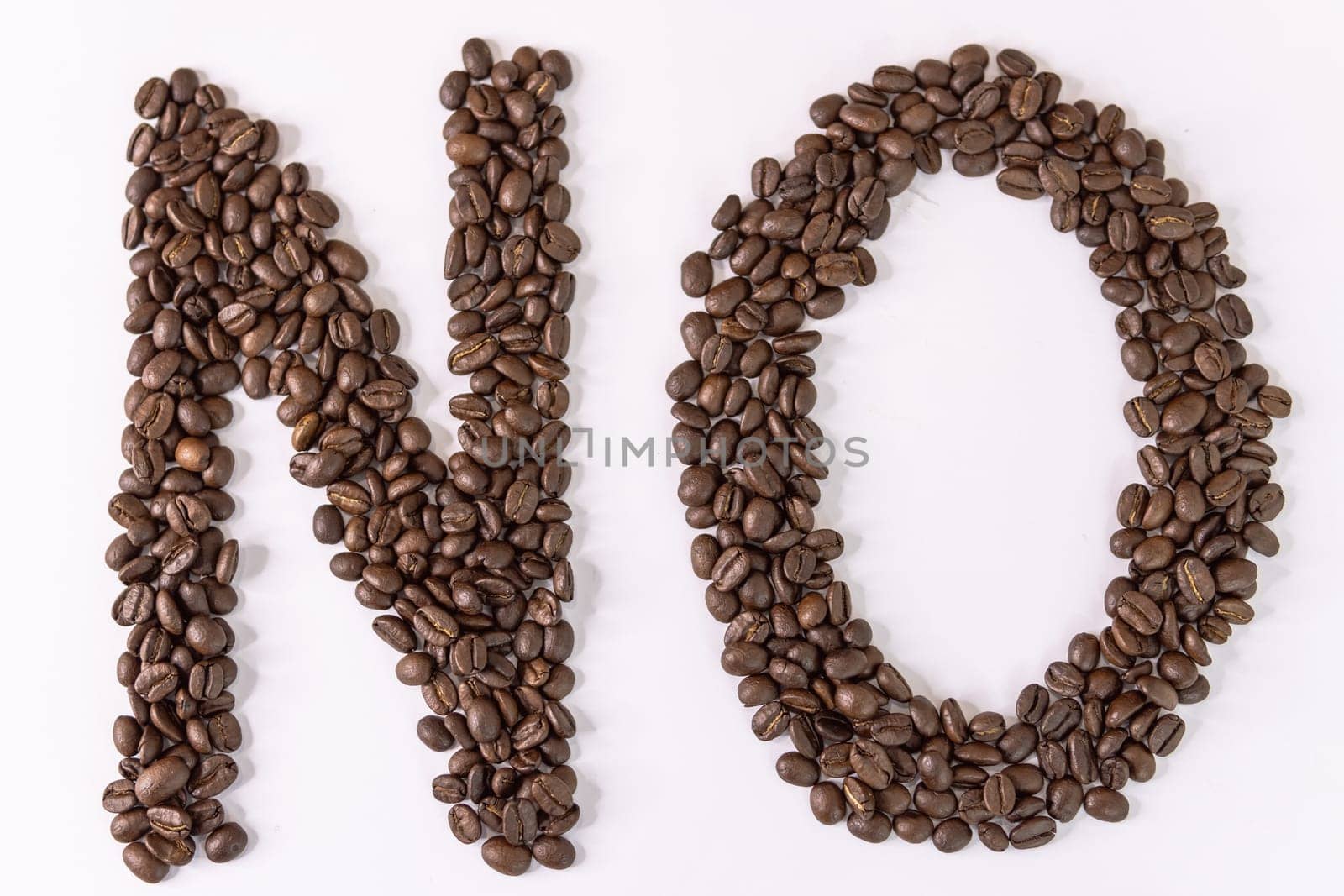 No is written with coffee beans on a white background. Roasted coffee beans on a white background.