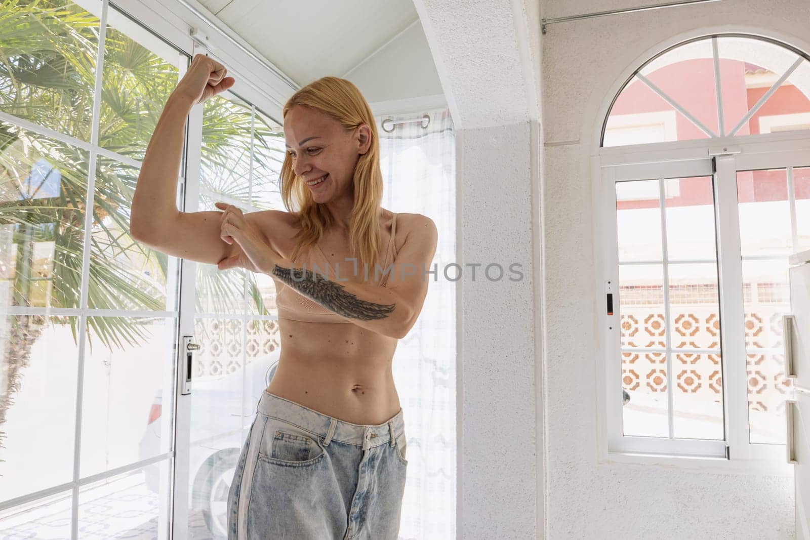 The concept of a successful diet. Cropped shot of a young woman in oversized jeans showing the results of her weight loss program,there is a place for an inscription. High quality photo