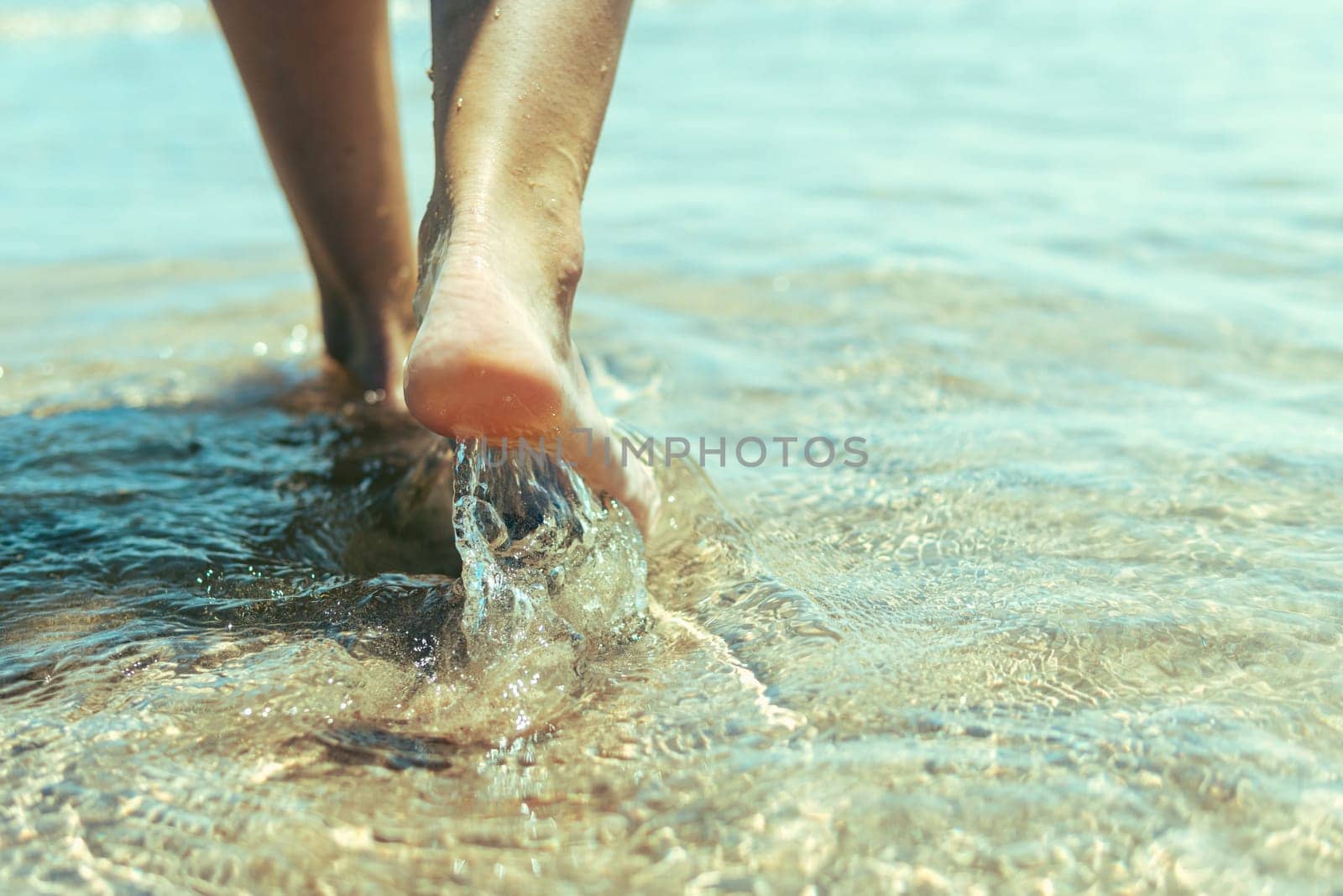 Vacation concept. Close up of female legs walking by the beach. by PopOff