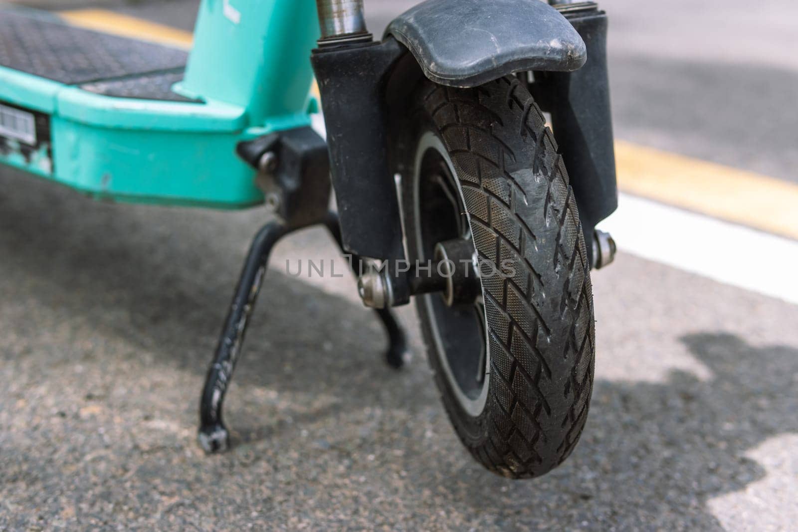 front wheel from an electric scooter close-up, the scooter stands on a leg on the street. High quality photo