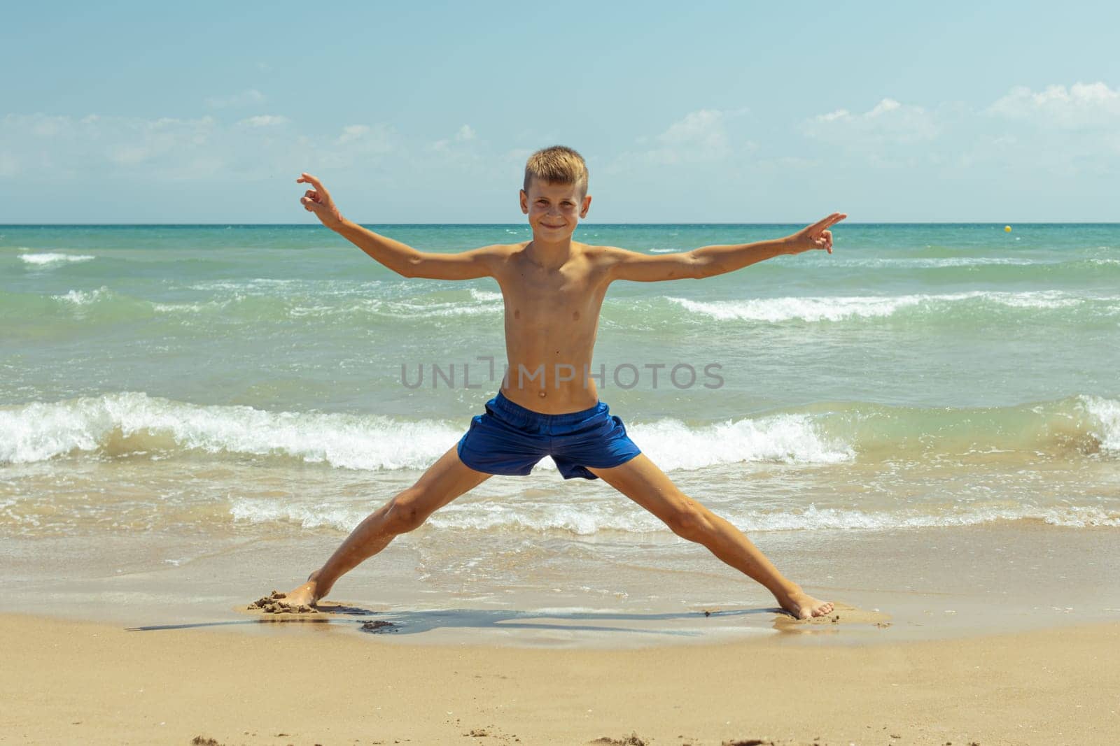 A happy boy of European appearance is walking on the beach. Summer holiday concept. High quality photo