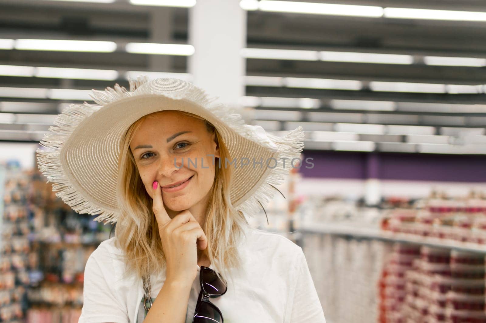 portrait of a smiling girl in a store,girl trying on a sun hat in a store.shopping concept by PopOff