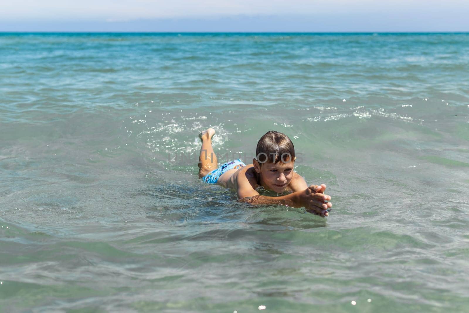 a boy of European appearance in the sea learns to swim.the concept of summer holidays.there is a place for an inscription,summer landscape with a child. High quality photo