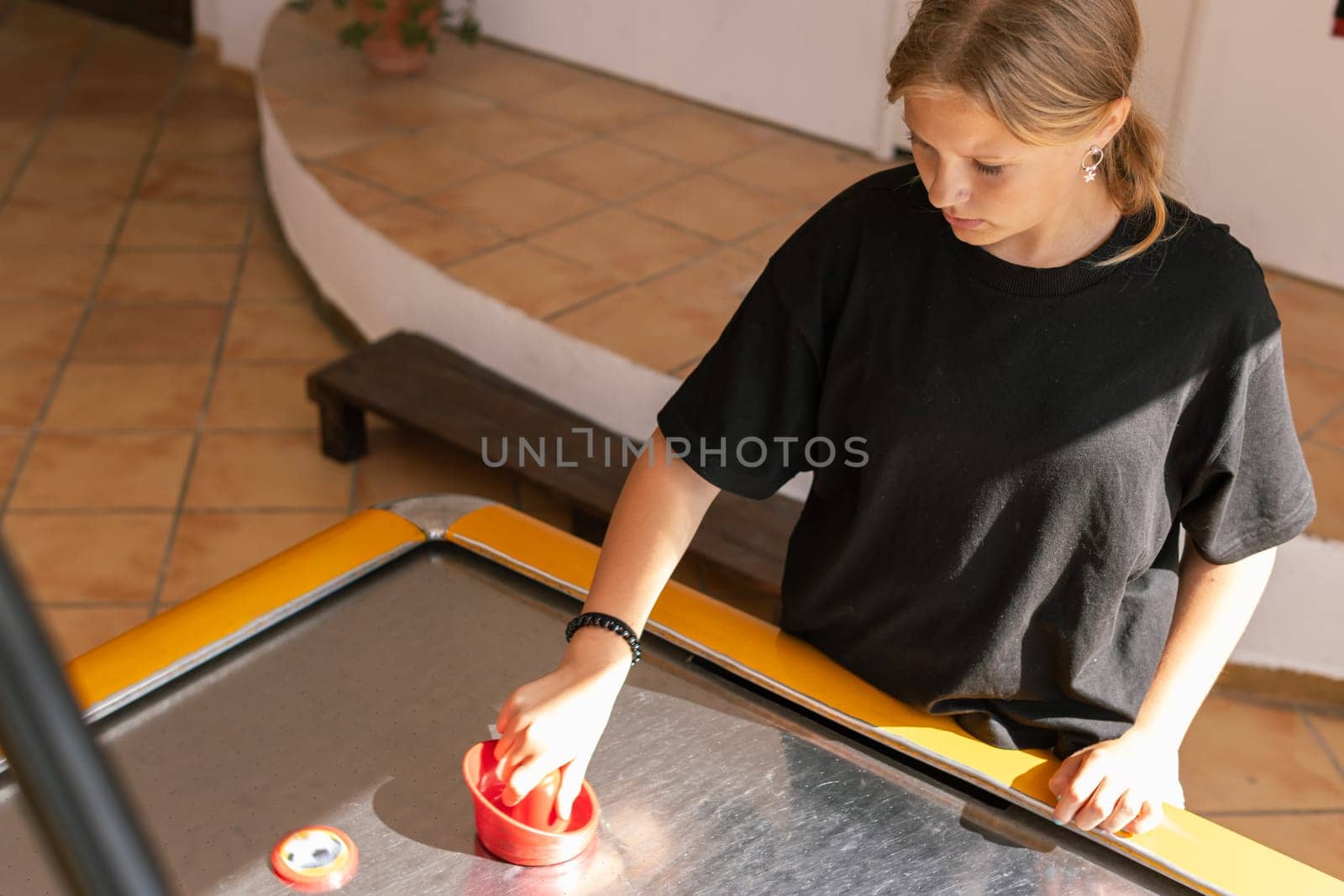 Cute teen girl plays air hockey arcade in game machine at an amusement park. High quality photo