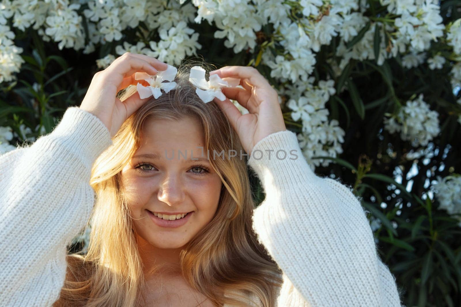 portrait of a teenage girl of European appearance, blonde hair, the girl stands on the street holding a white flower near her eye there is a place for an inscription. High quality photo