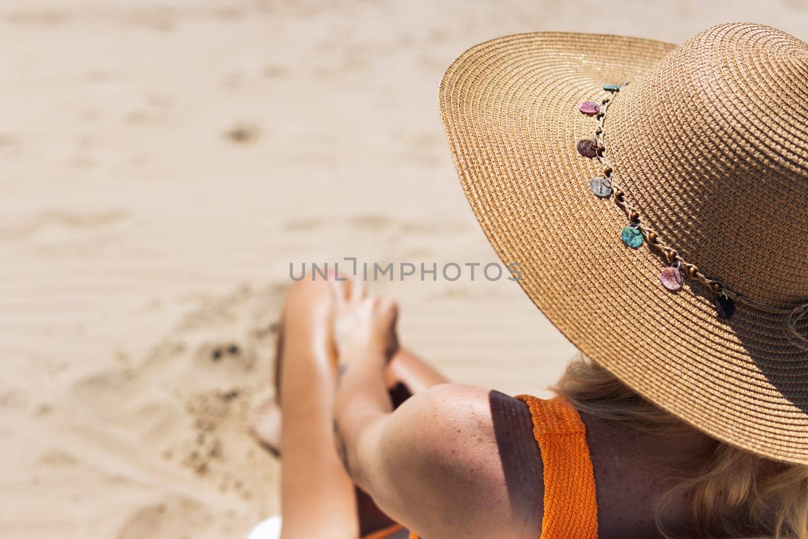 a tanned girl in a hat sits in a sun lounger, rear view, a beautiful seascape there is a place for an inscription from the left. High quality photo