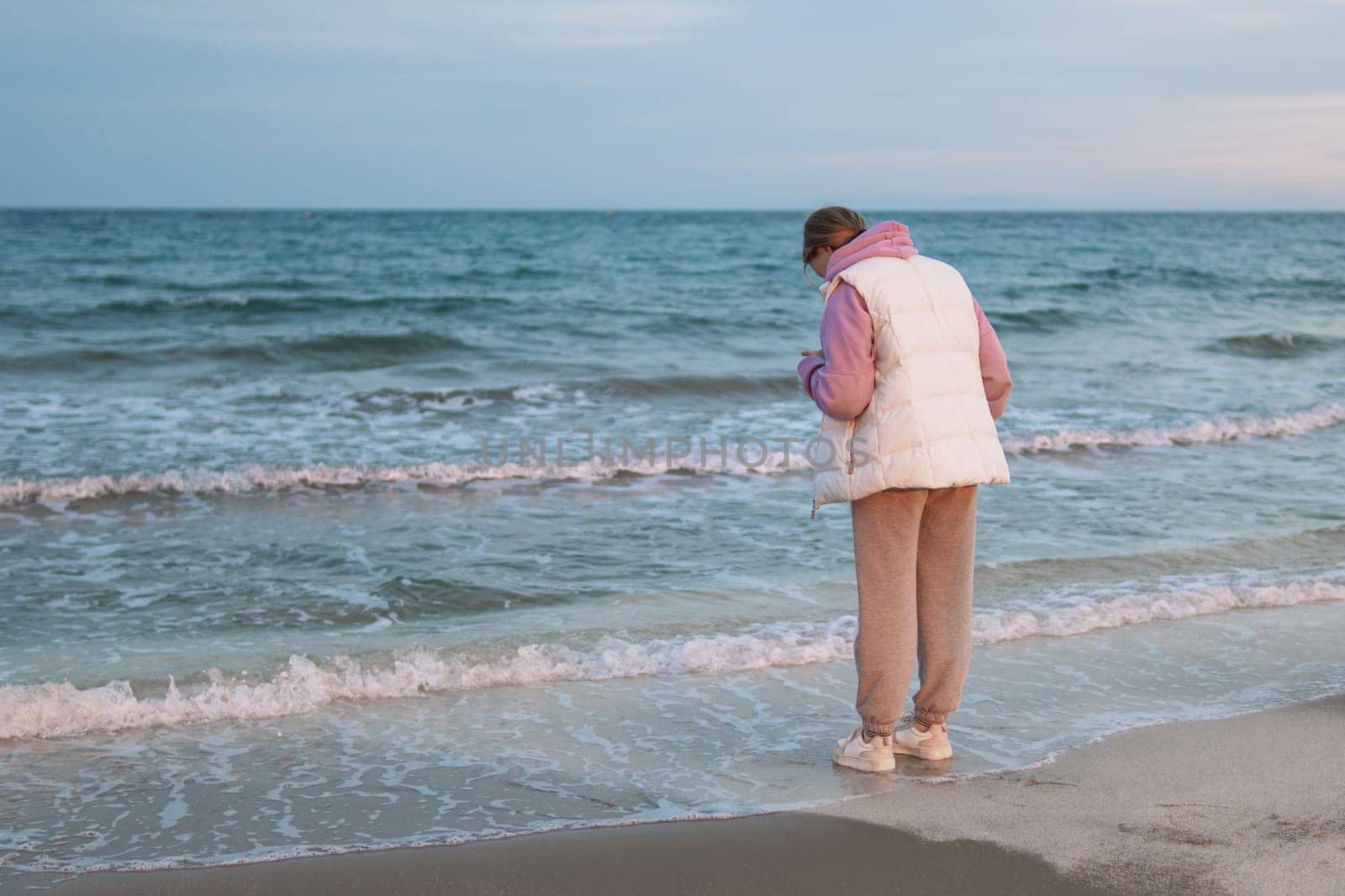 A young girl standing alone near the coast of the sea ocean. Fresh spring morning and dramatic sky. High quality photo