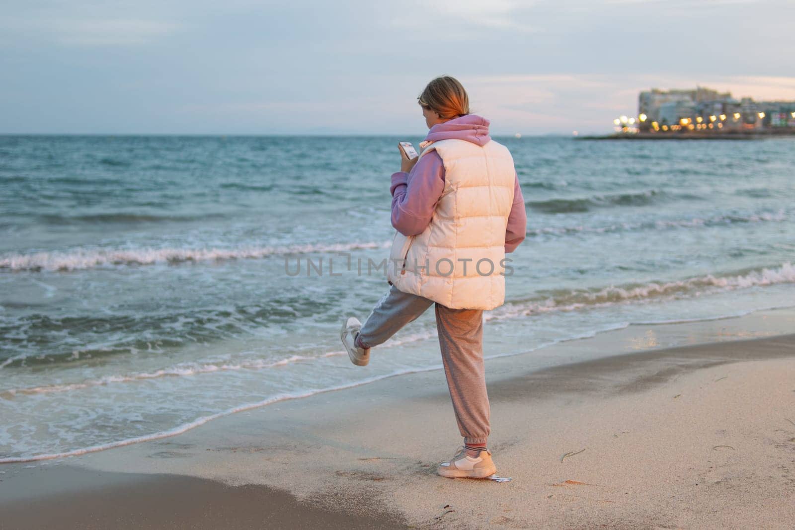 A teenager communicates on the phone with a guy and is sad while standing near the sea, the concept of a difficult age in teenagers. High quality photo