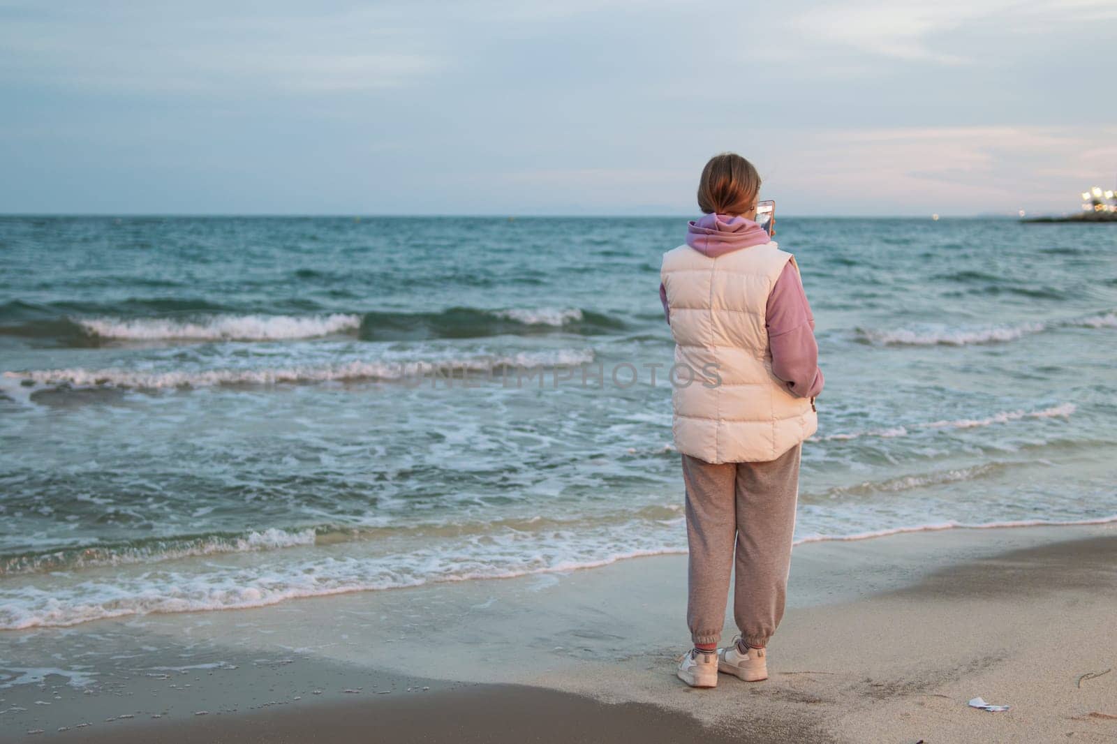 A teenager communicates on the phone with a guy and is sad while standing near the sea, the concept of a difficult age in teenagers. High quality photo