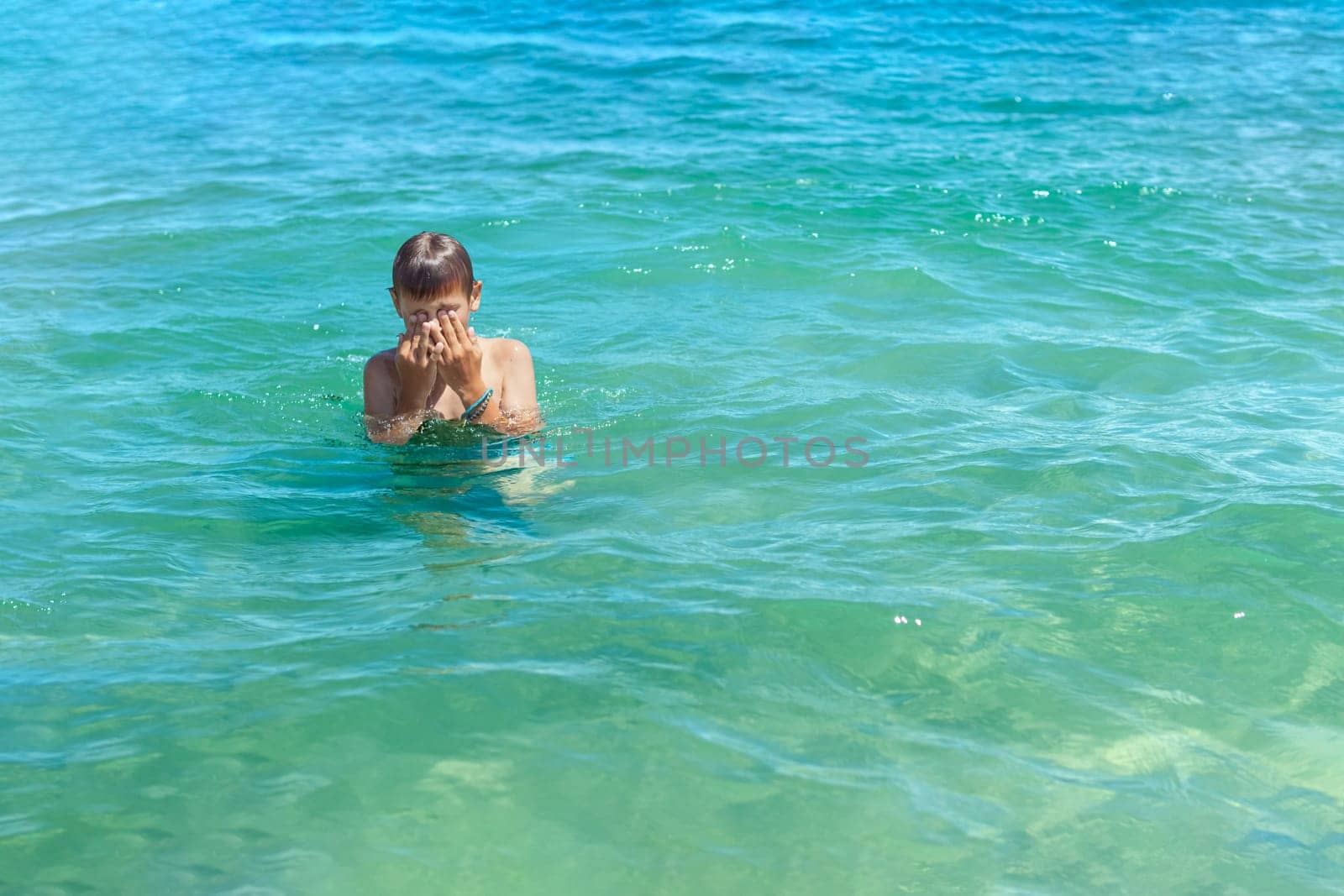 a boy of European appearance in the sea learns to swim.the concept of summer holidays.there is a place for an inscription,summer landscape with a child. High quality photo