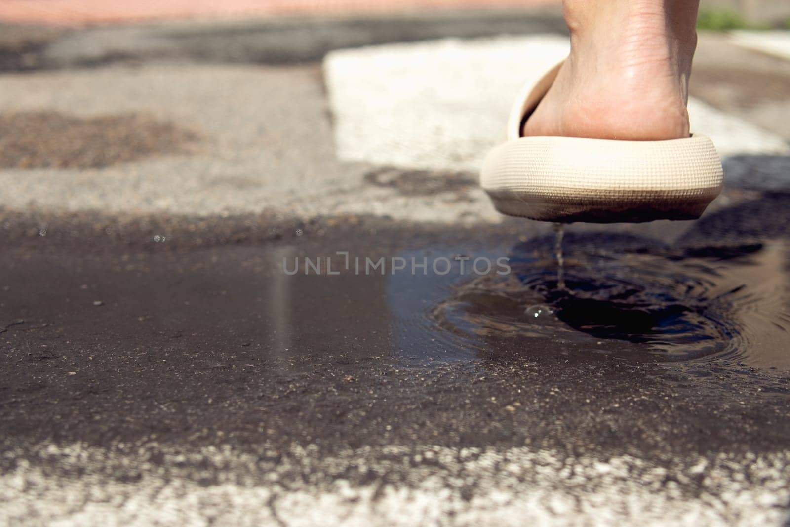 close-up on the legs in brown slippers, female legs cross the puddle on the street close-up on the by PopOff