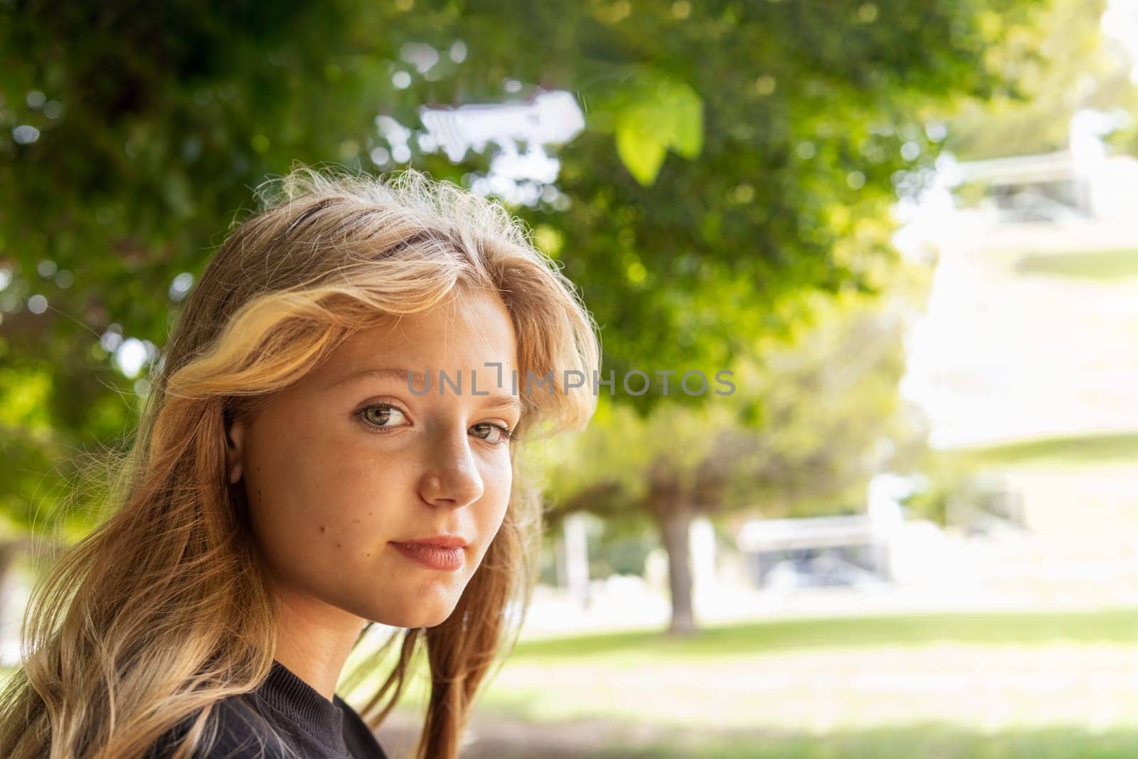 portrait of a teenage girl with blond hair, the girl sits in the park and looks at the camera by PopOff