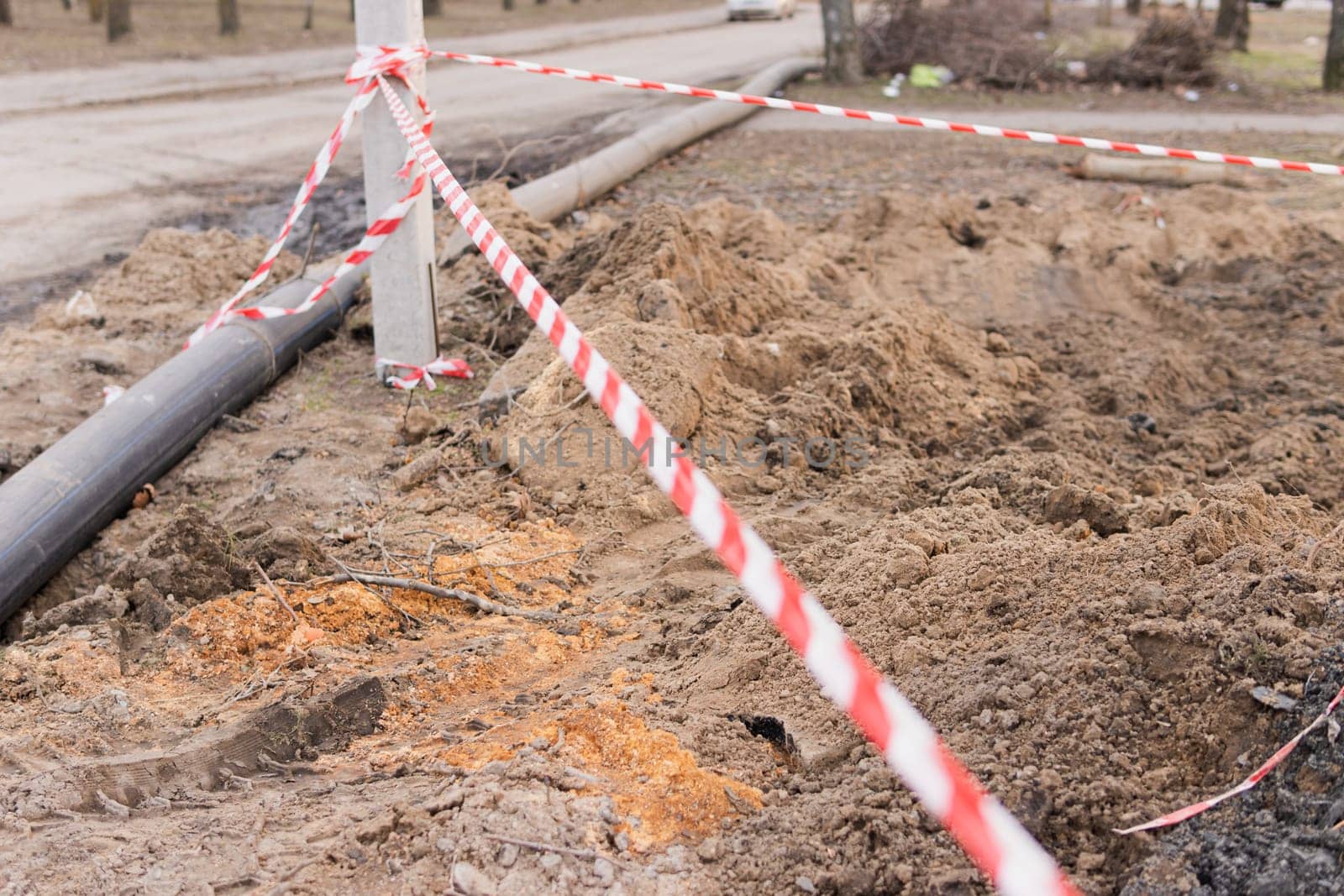 Plastic pipes in the ground during construction on the street. excavated road fenced with signal tape.High quality photo