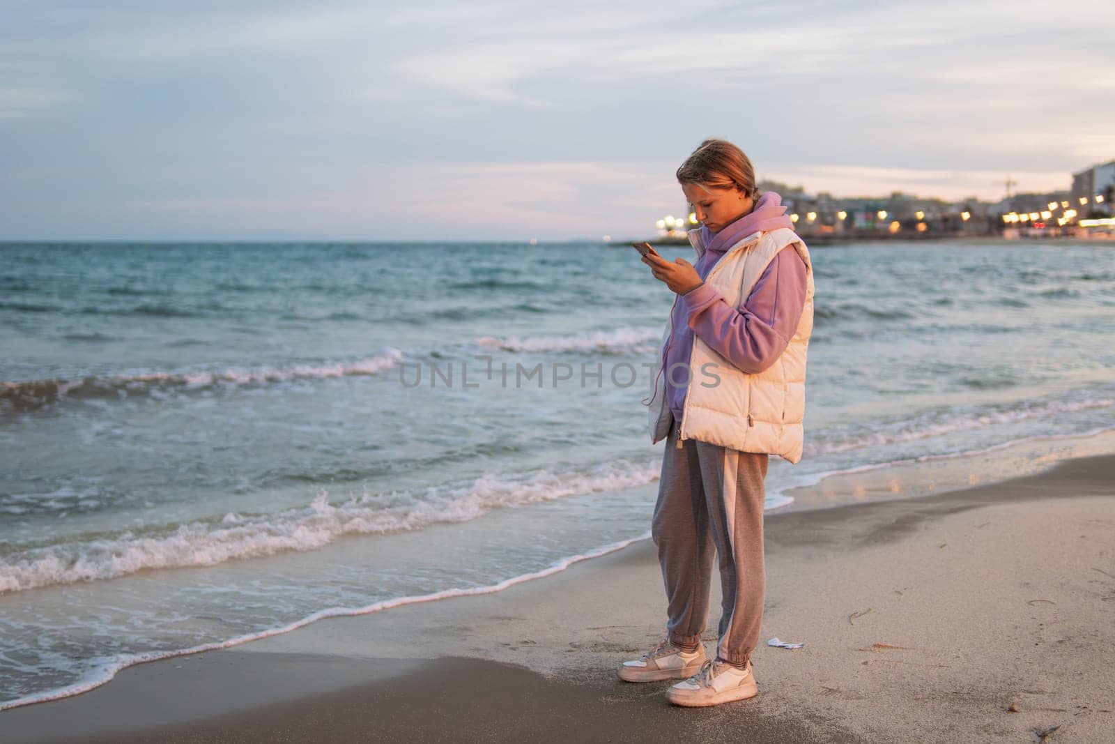 A teenager communicates on the phone with a guy and is sad while standing near the sea, the concept of a difficult age in teenagers. High quality photo