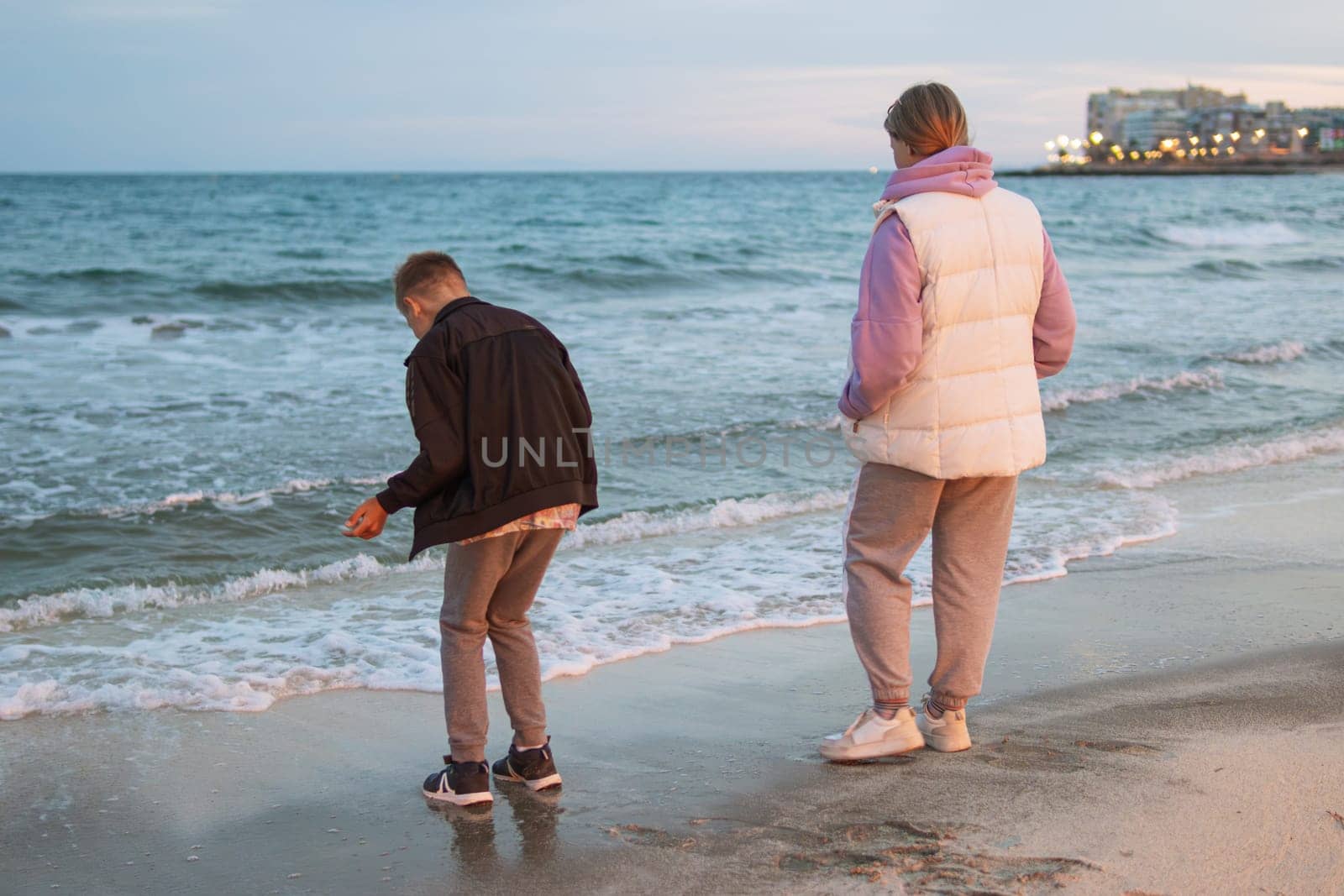 Teenagers stand on the beach, look at the sea, turned their backs to the camera by PopOff