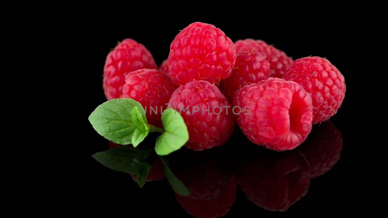 Raspberries with leaves isolated on black background