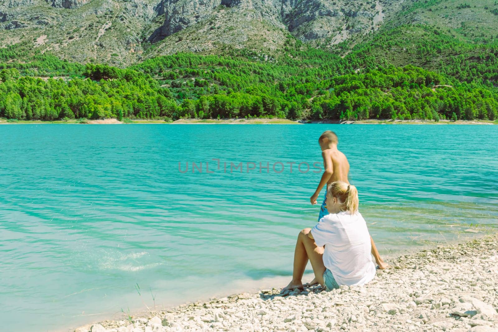 beautiful mountain landscape with a girl and a child against the backdrop of mountains and a lake. High quality photo