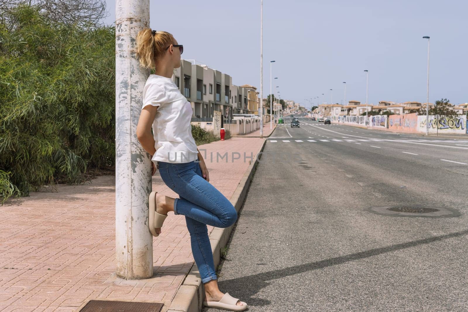 the girl stands on the road and looks at the cars in casual clothes. High quality photo