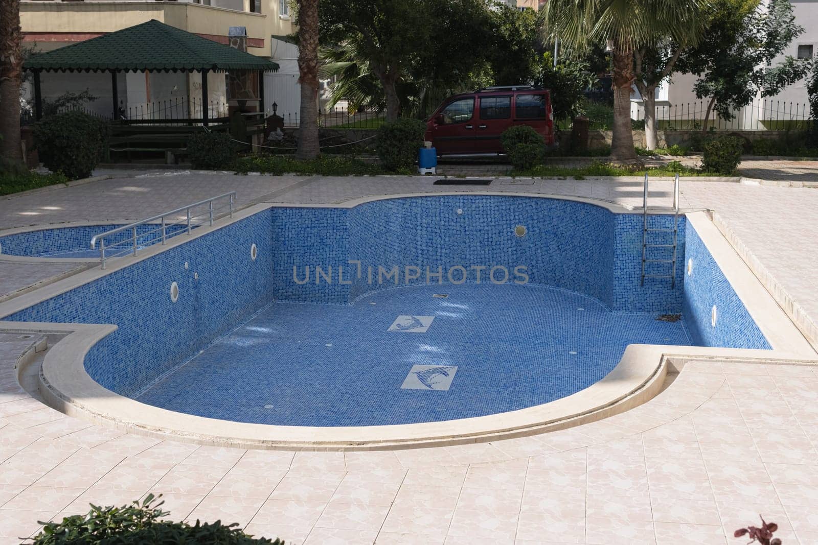 new pool without water in the hotel in the backyard, tiled,green trees by PopOff