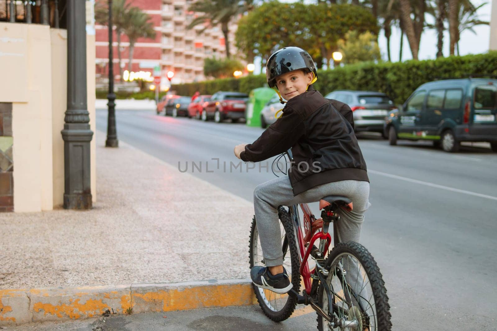 a child of European appearance rides a bicycle, wearing a black helmet in casual clothes, by PopOff