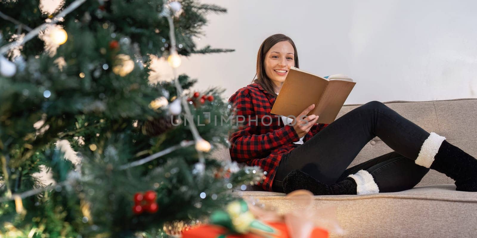 Caucasian woman reading book and relaxation on couch on Christmas holiday.