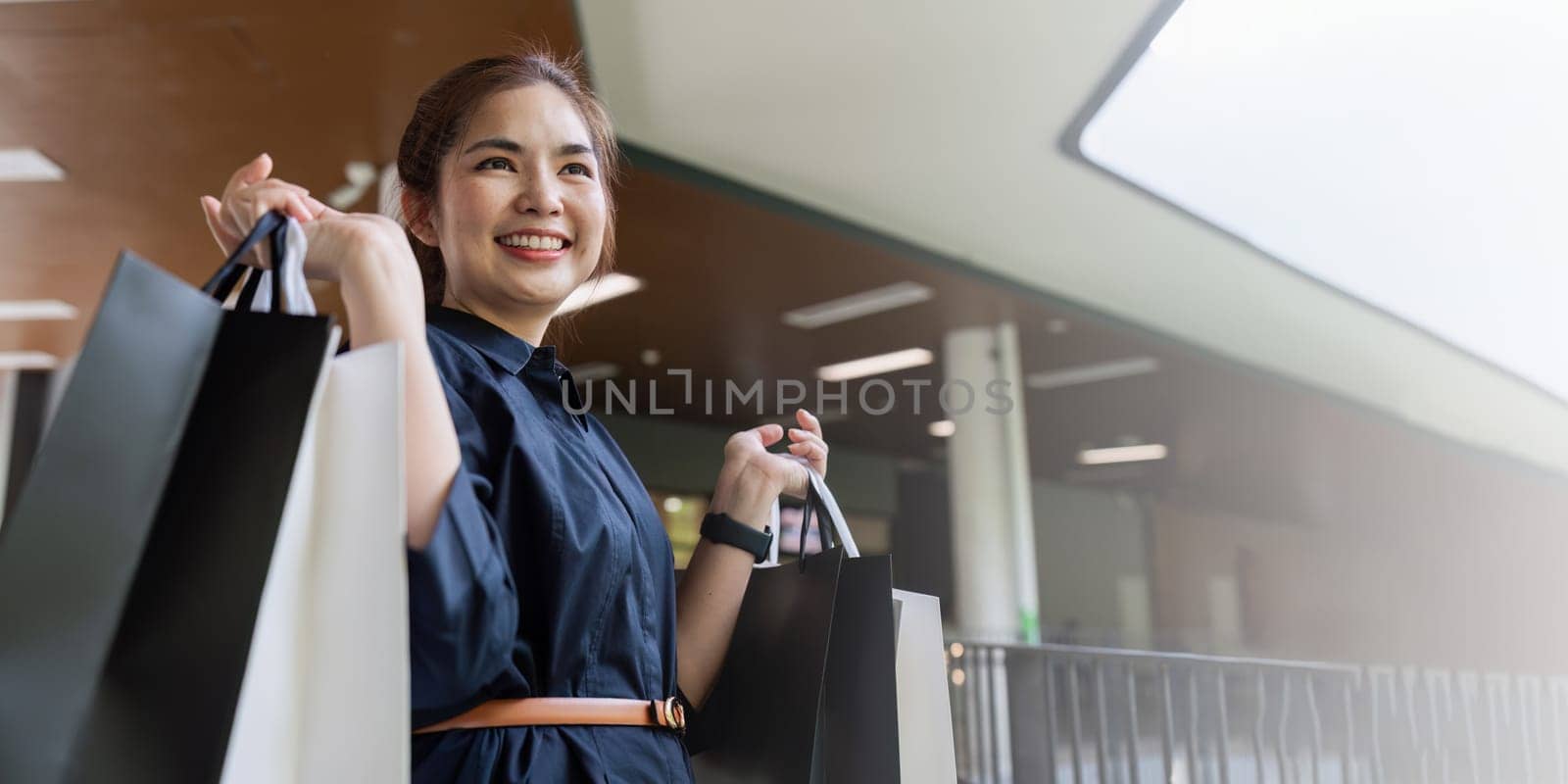 Young asian woman in shopping. Fashion woman in black with shopping bag walking around the city after shopping. Black friday.