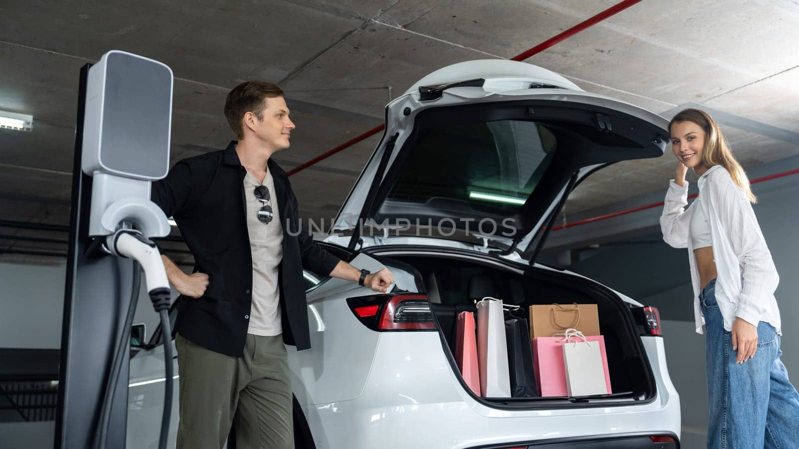 Young couple travel with EV electric car to shopping center parking lot innards by biancoblue