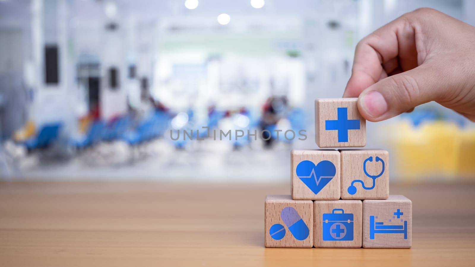 Health insurance and healthcare concept, human hand holds wooden block with icons about health insurance and healthcare access, retirement planning on wooden background.