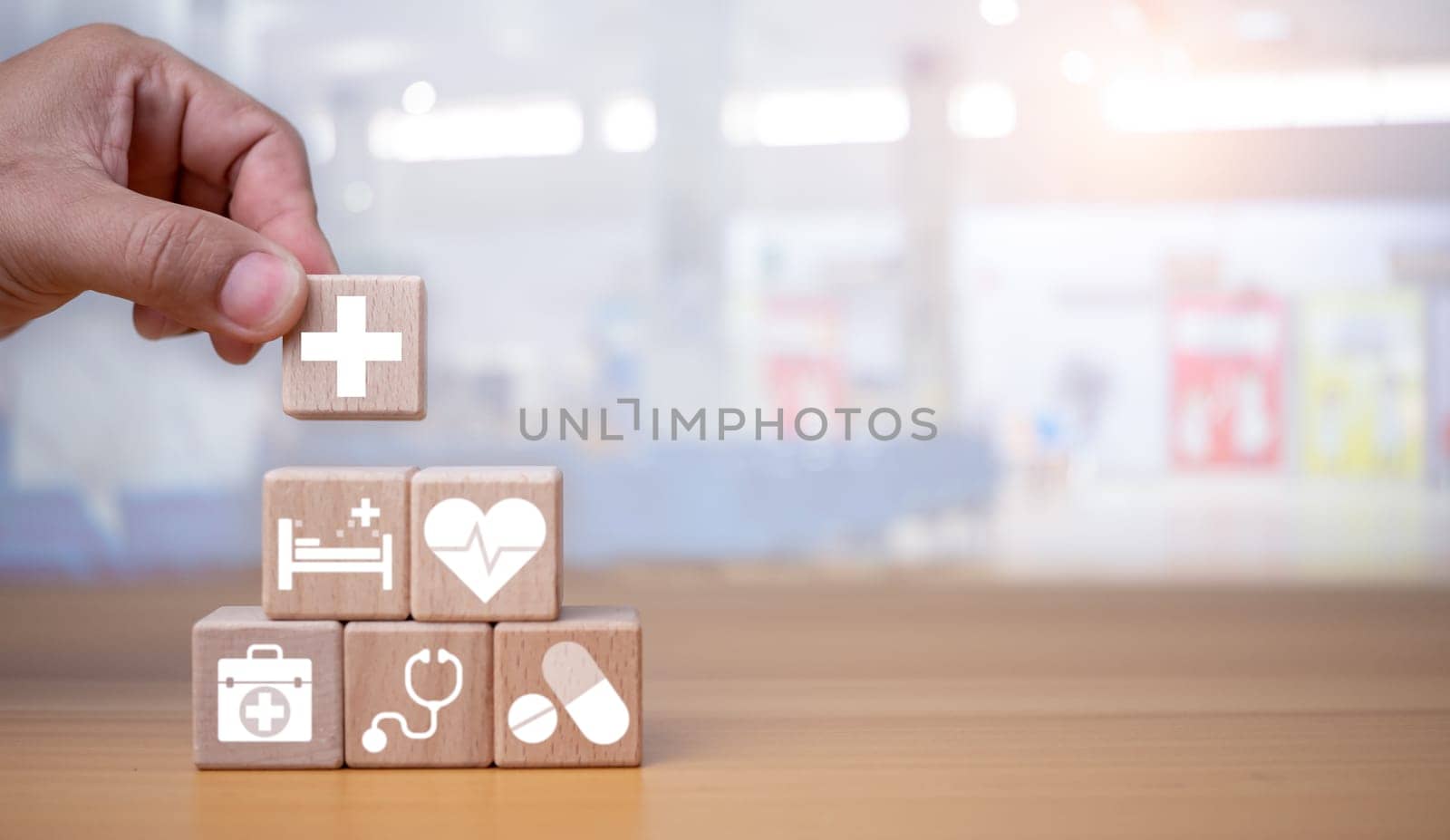 Health insurance and healthcare concept, human hand holds wooden block with icons about health insurance and healthcare access, retirement planning on wooden background. by Unimages2527