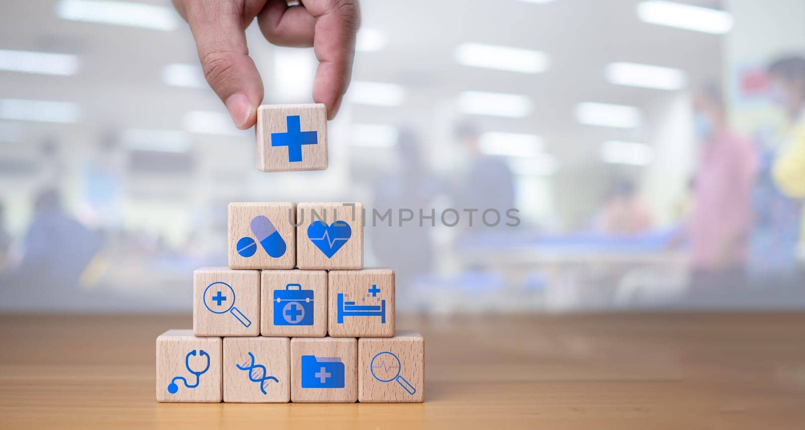 Health insurance and healthcare concept, human hand holds wooden block with icons about health insurance and healthcare access, retirement planning on wooden background. by Unimages2527