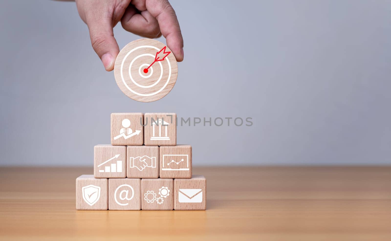 Businessman's hands hold a circular wooden board with printed target icons, business goals and objectives concept, business competition.