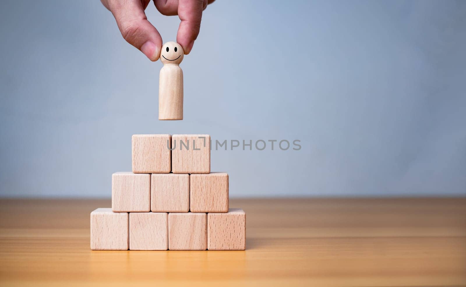 Business and HR concept for leaders and team leaders, human hand holding a wooden doll placed on a wooden block. by Unimages2527