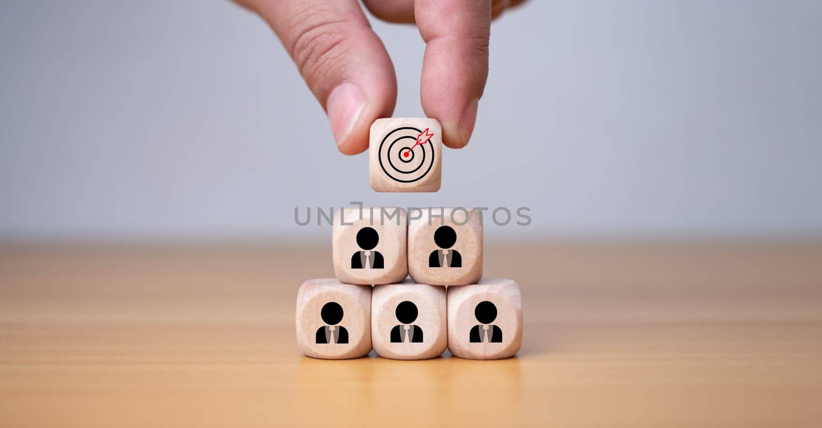 Human hand holding a wooden block which prints a target icon, Business goals and objectives concept, business competition. by Unimages2527