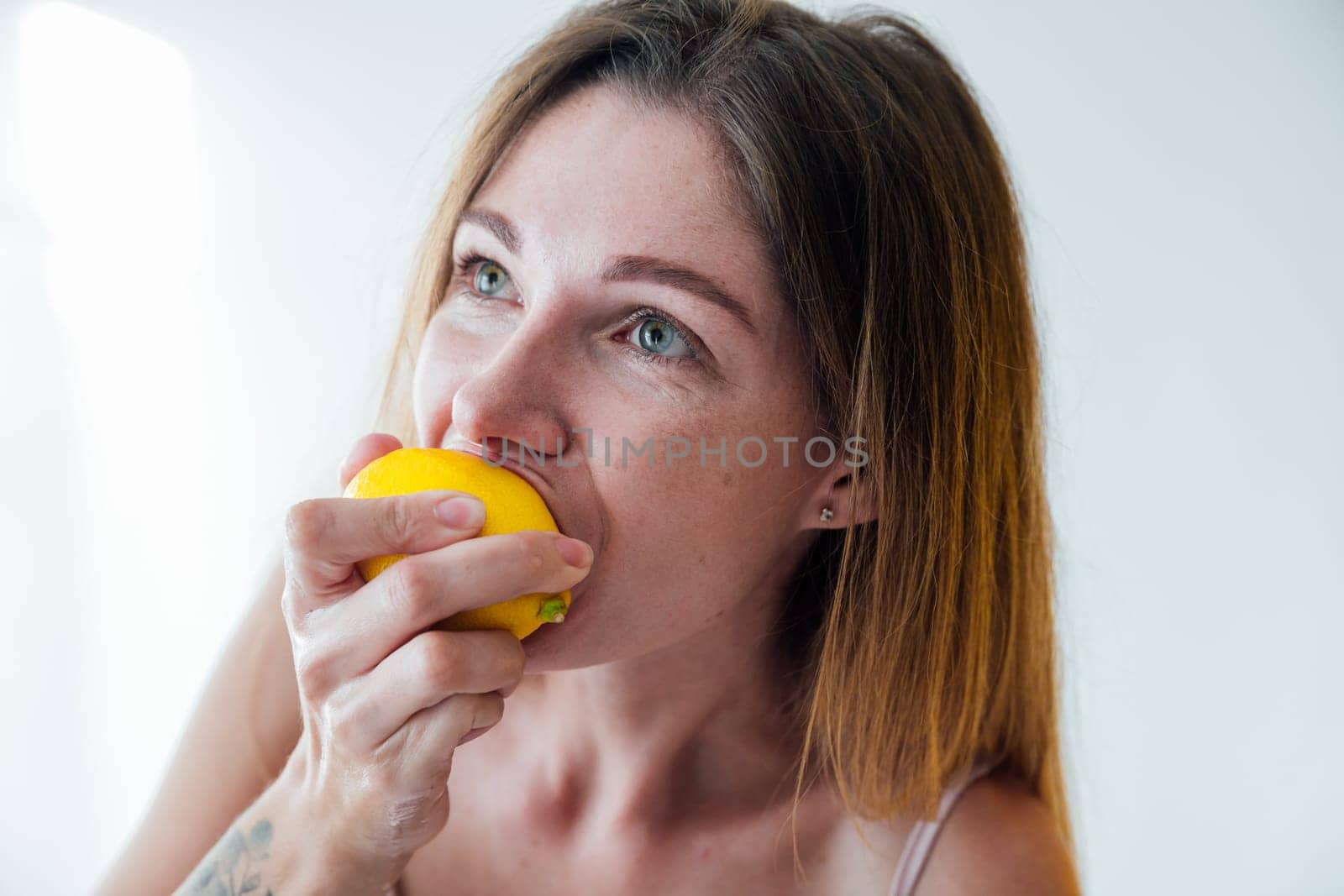 woman blonde eats sour lemon fruit yellow citrus by Simakov