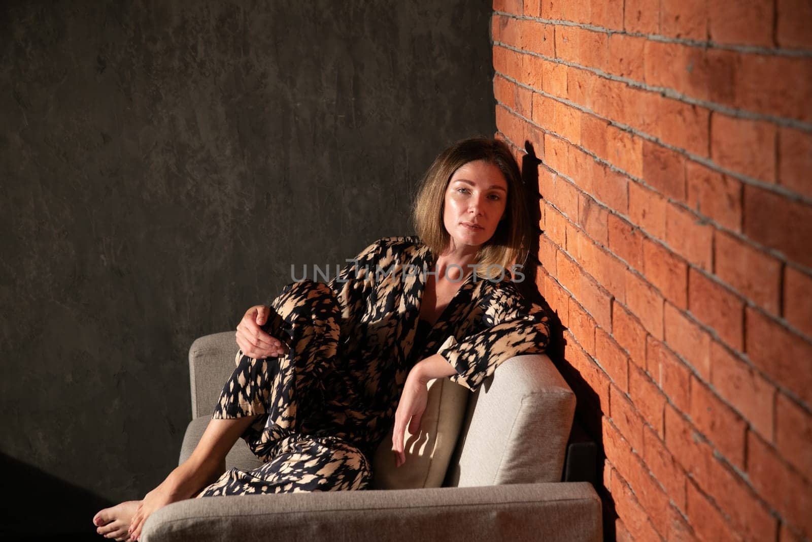 woman sitting on a couch against a red brick wall