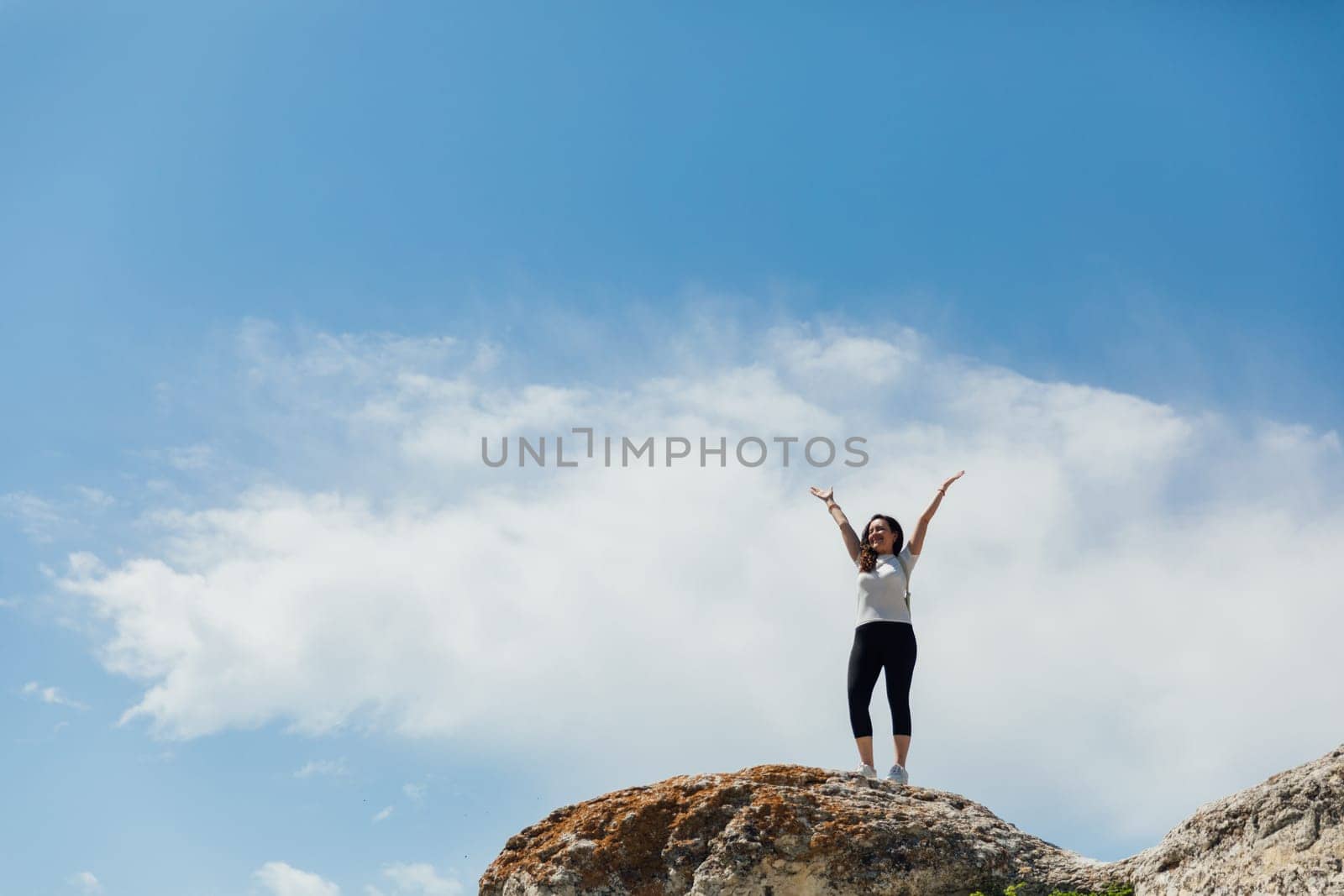 a woman stands on a mountain and pulls her arms up a hiking trip