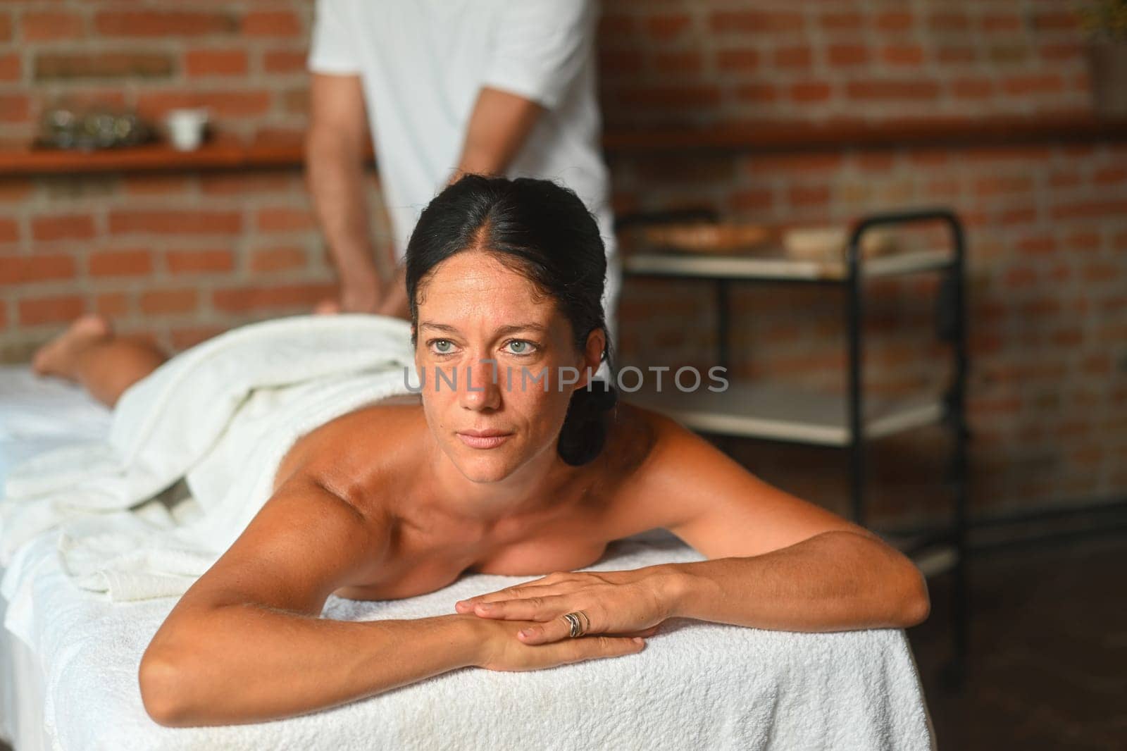hispanic brunette adult fit woman ready for being massage by physiotherapist in the therapeutical bed