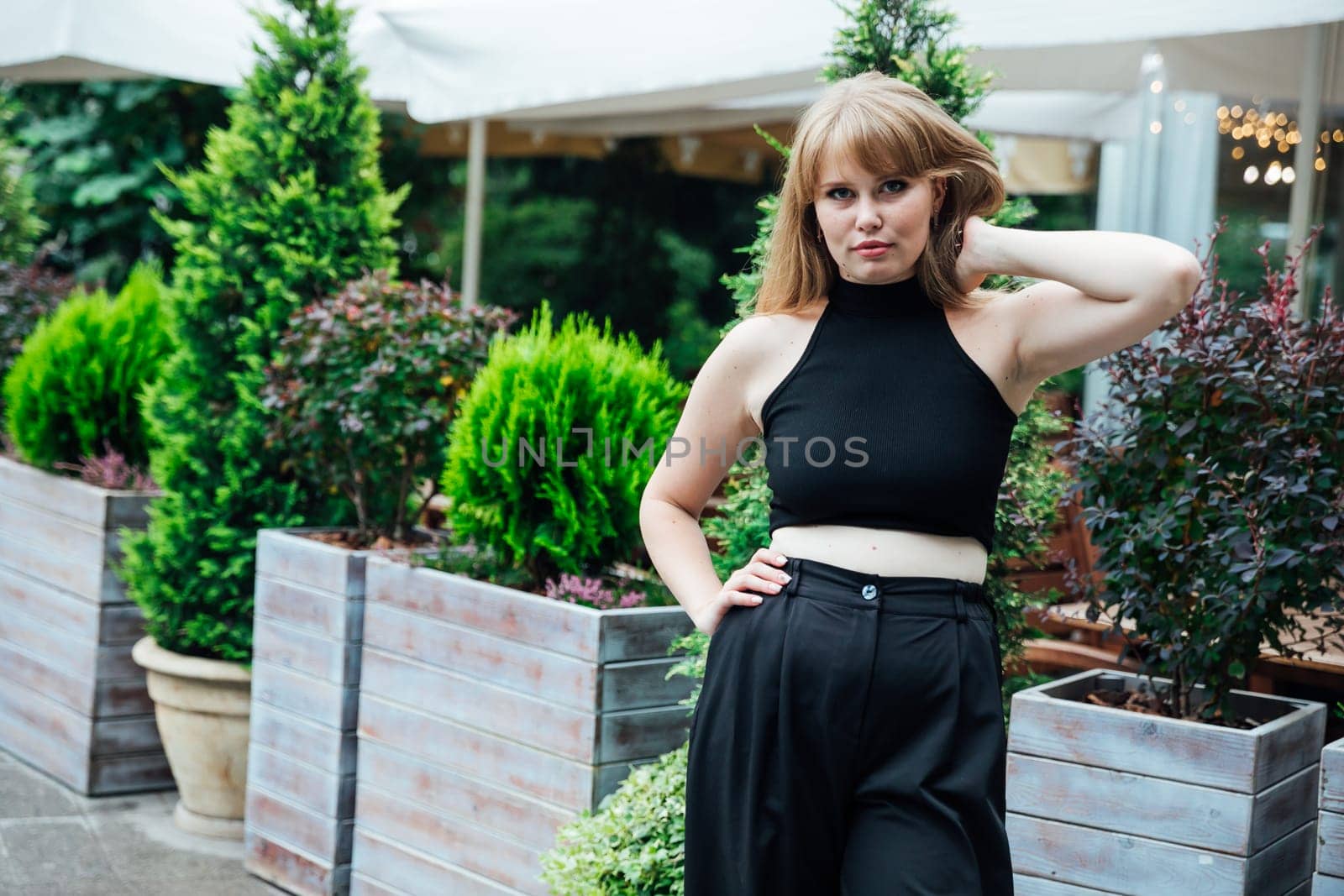 beautiful woman in dark clothes stands at green plants