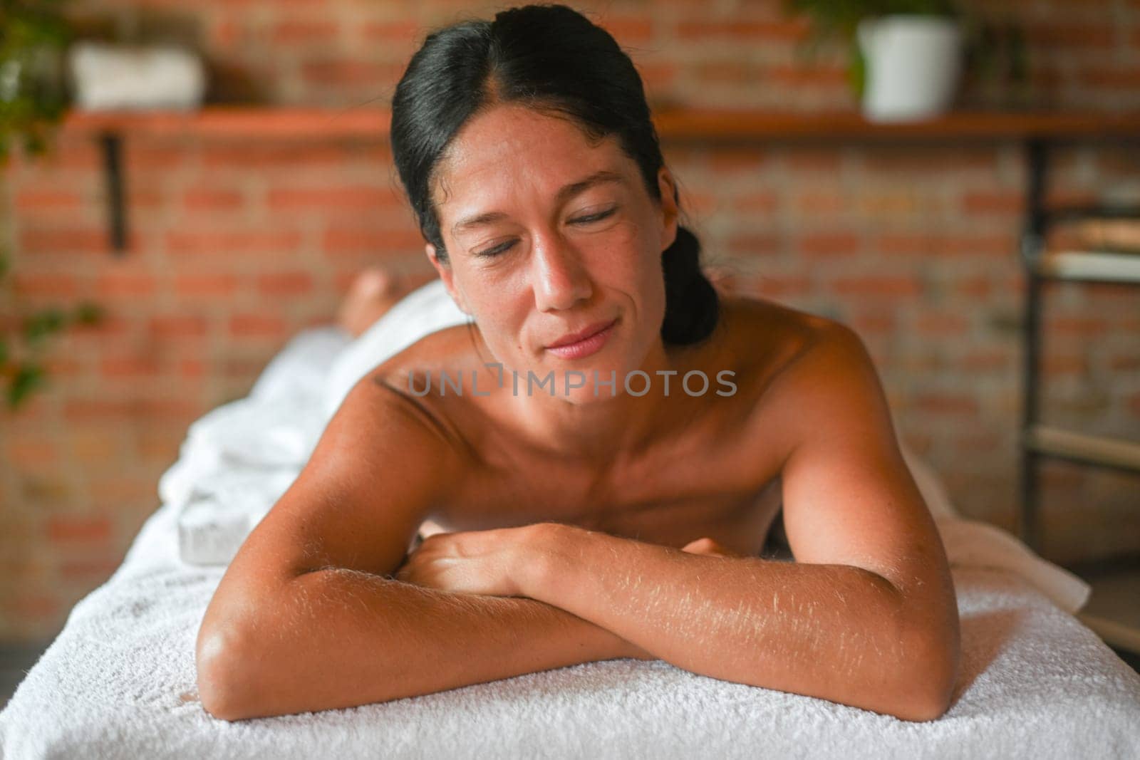 hispanic brunette adult fit woman ready for being massage by physiotherapist in the therapeutical bed