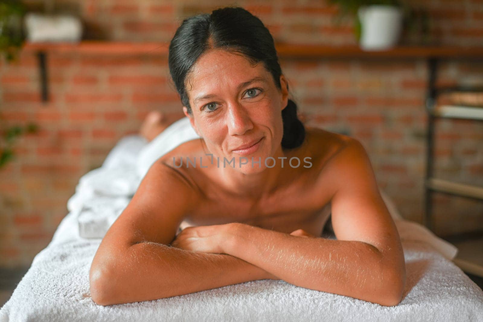 hispanic brunette adult fit woman ready for being massage by physiotherapist in the therapeutical bed