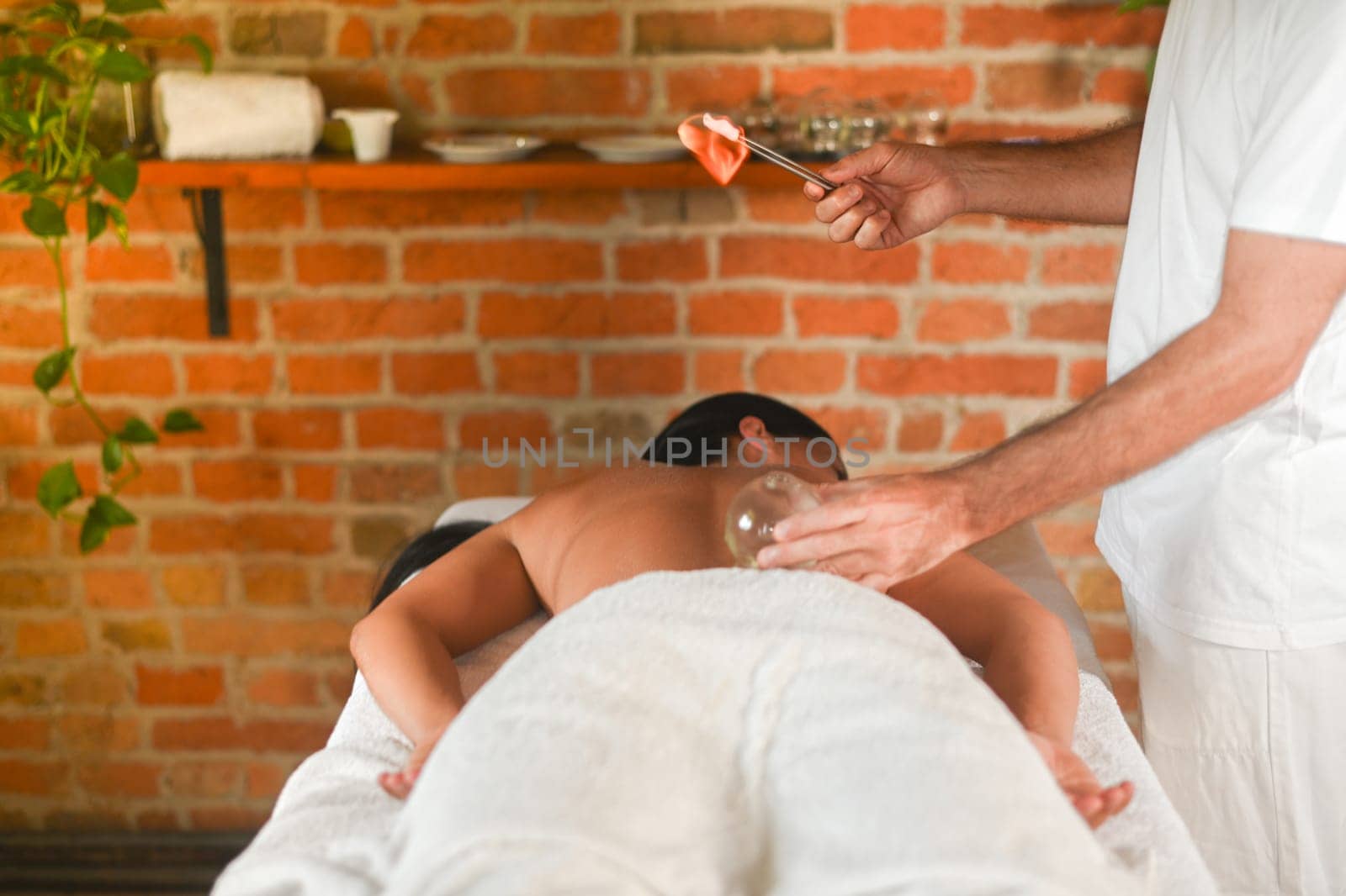 physiotherapist perform cupping therapy with suction massage to hispanic adult fit woman in the therapeutical bed for stress relief