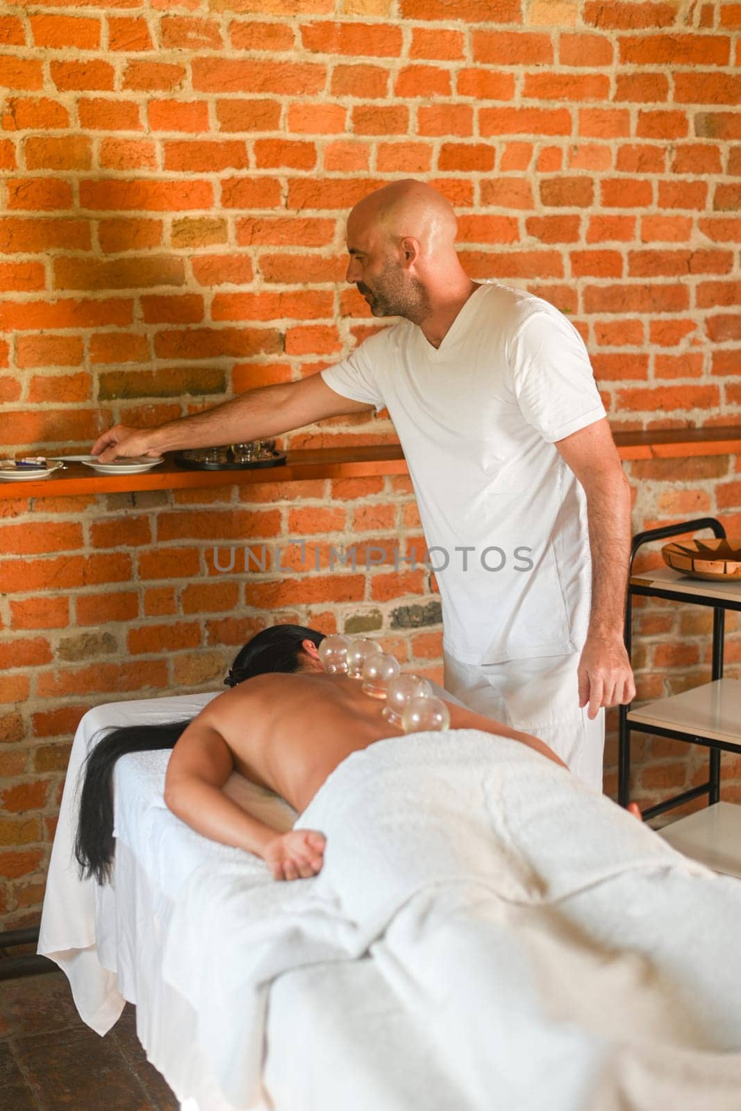 physiotherapist perform cupping therapy with suction massage to hispanic adult fit woman in the therapeutical bed for stress relief