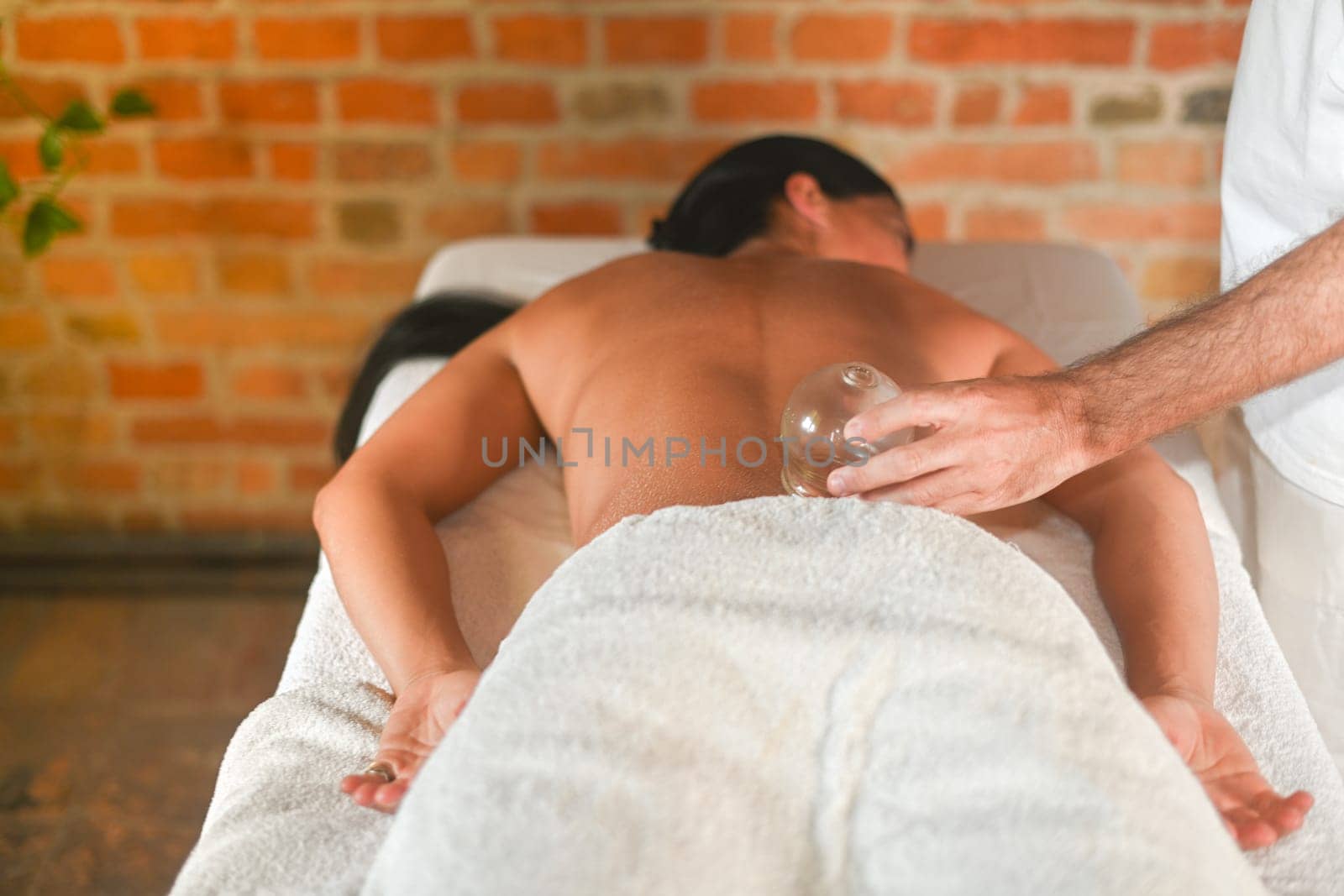 physiotherapist perform suction massage to hispanic adult fit woman in the therapeutical bed by verbano