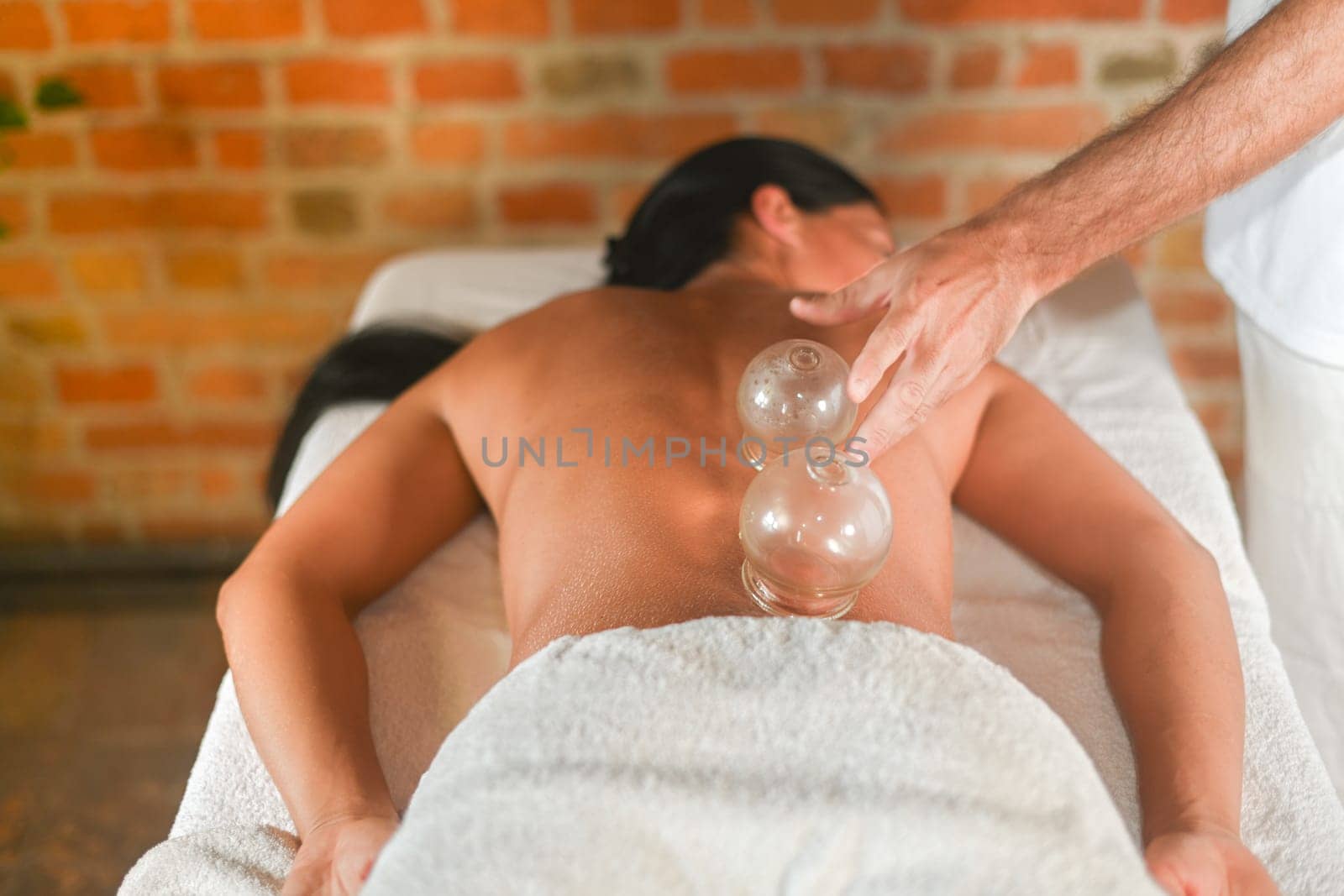 physiotherapist perform cupping therapy with suction massage to hispanic adult fit woman in the therapeutical bed for stress relief