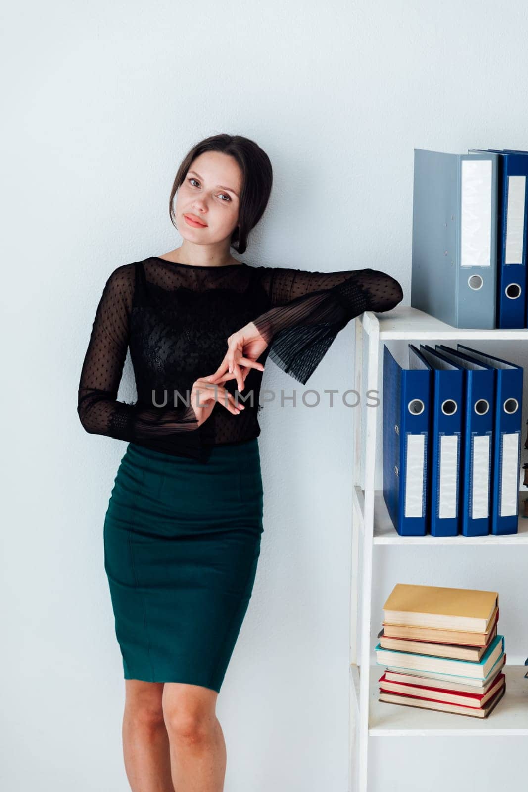 a business woman stands at a shelf with folders in the office by Simakov